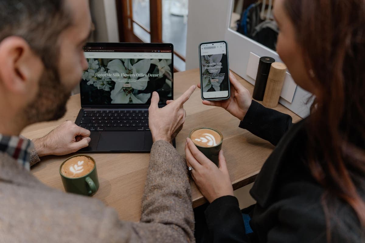 A Luma client being shown their new website on a laptop and phone over coffee